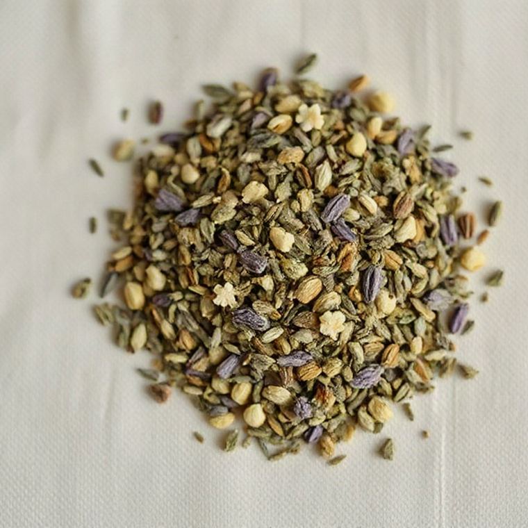 Loose dried Sleep Tea blend — chamomile flowers, lavender buds and soft green leaf — scattered on ivory linen.
